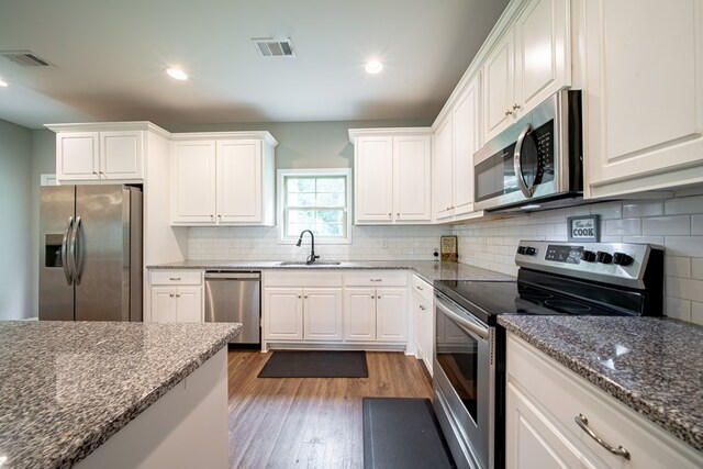 402 Lee Road 2203, Phenix City, AL 36870 - kitchen with appliances with stainless steel finishes, wood finished floors, white cabinets, tasteful backsplash, and dark stone counters