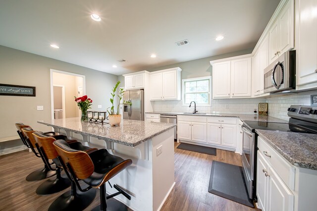 402 Lee Road 2203, Phenix City, AL 36870 - kitchen featuring appliances with stainless steel finishes, a center island, white cabinets, backsplash, and a breakfast bar area
