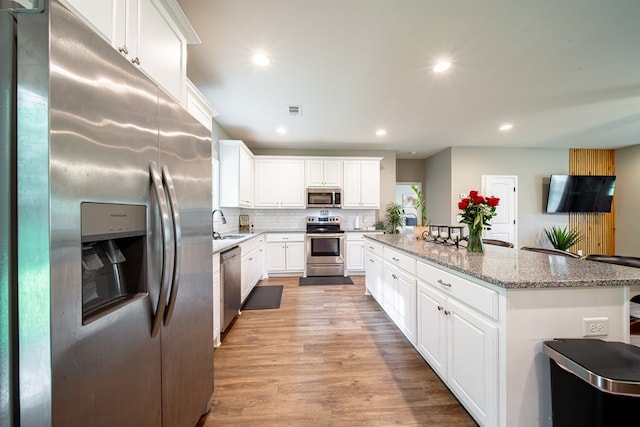 402 Lee Road 2203, Phenix City, AL 36870 - kitchen featuring stainless steel appliances, a center island, white cabinets, light wood-type flooring, and light stone counters