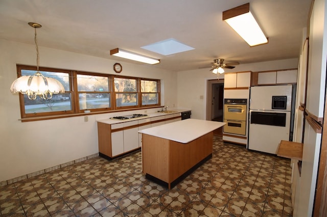 kitchen with hanging light fixtures, a center island, sink, white appliances, and white cabinets