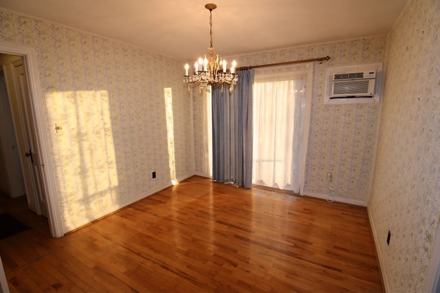 unfurnished room featuring hardwood / wood-style flooring, a wall mounted AC, and a notable chandelier