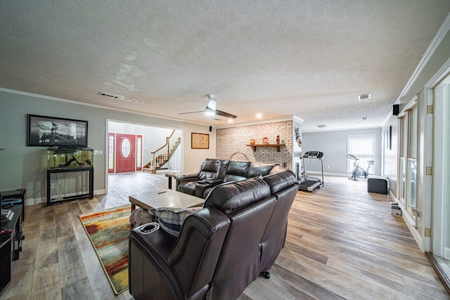 living area featuring visible vents, crown molding, wood finished floors, stairway, and a textured ceiling