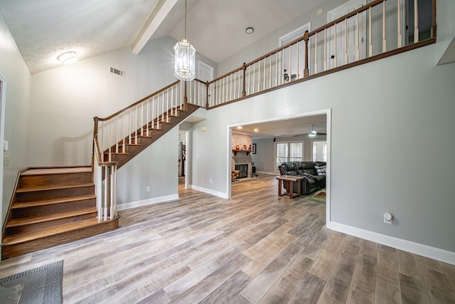 unfurnished living room with high vaulted ceiling, visible vents, wood finished floors, and stairway