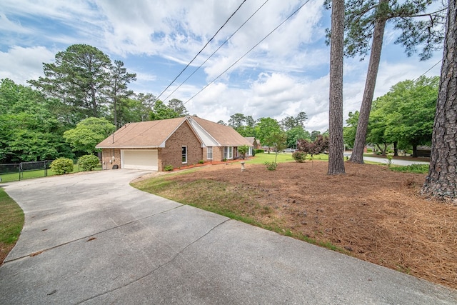 view of front of property with brick siding, an attached garage, fence, and driveway