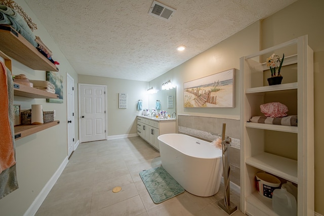 bathroom with visible vents, tile patterned flooring, vanity, a textured ceiling, and a freestanding bath