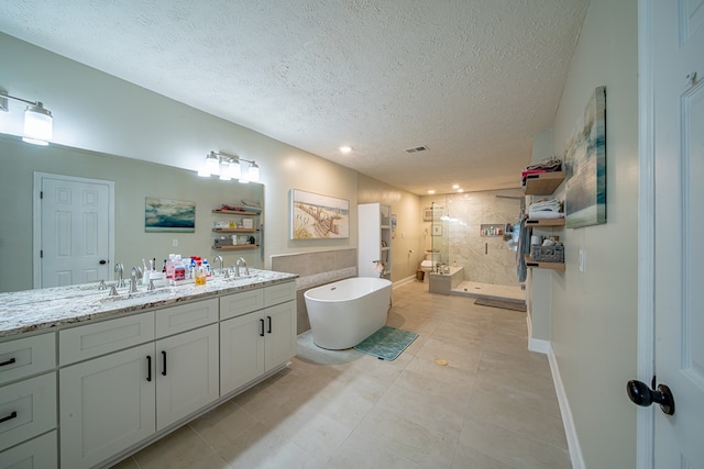 bathroom with double vanity, a freestanding tub, a textured ceiling, a sink, and a stall shower