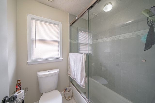 full bathroom featuring toilet, a shower with door, baseboards, and a textured ceiling