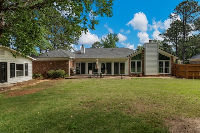 back of property with a chimney, a patio area, brick siding, and roof with shingles