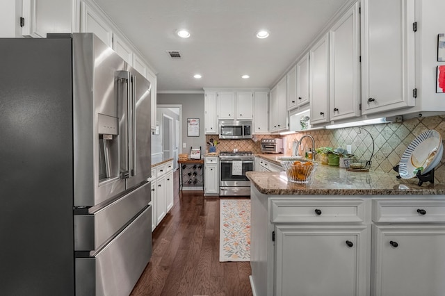 kitchen with stainless steel appliances, a sink, white cabinetry, ornamental molding, and dark wood finished floors