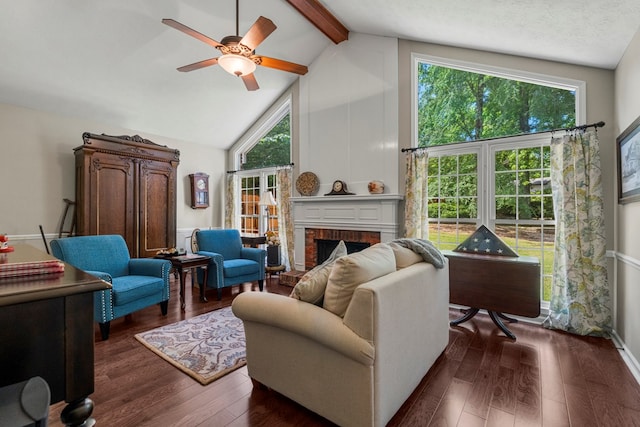 living area with dark wood-type flooring, beamed ceiling, high vaulted ceiling, a ceiling fan, and a brick fireplace