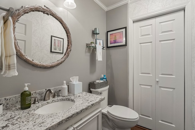 half bath with crown molding, toilet, vanity, and a closet