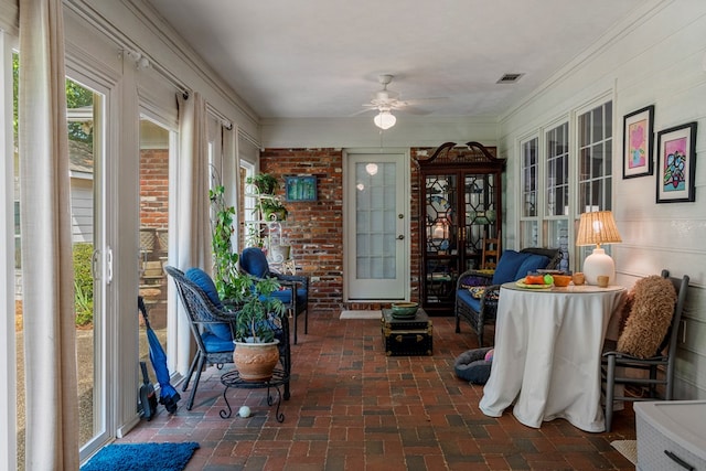 sunroom featuring brick floors, plenty of natural light, and crown molding