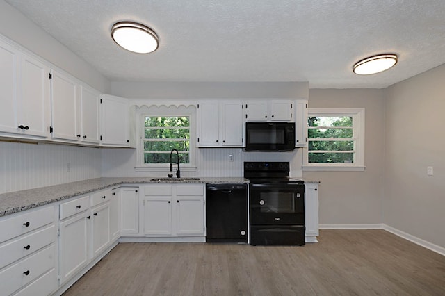3122 Glenwood Dr, Columbus, GA 31906 - kitchen featuring black appliances, light wood-style flooring, white cabinetry, healthy amount of natural light, and a textured ceiling