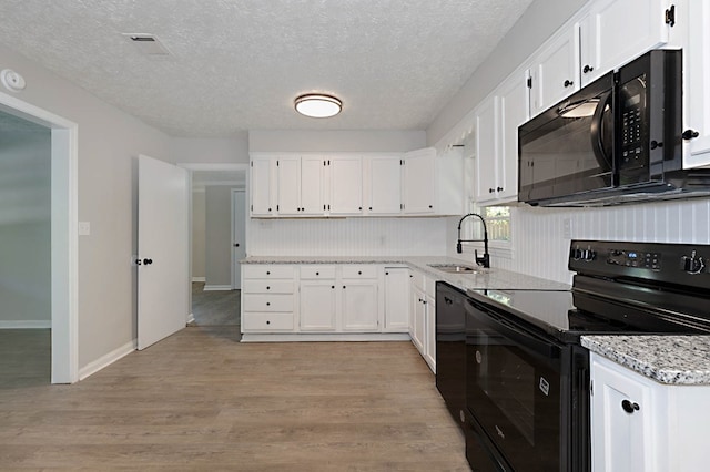 3122 Glenwood Dr, Columbus, GA 31906 - kitchen featuring black appliances, white cabinetry, light wood finished floors, and a textured ceiling