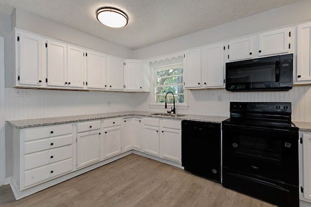 3122 Glenwood Dr, Columbus, GA 31906 - kitchen featuring black appliances, light wood-type flooring, white cabinets, light stone countertops, and a textured ceiling