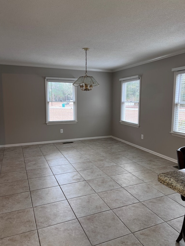 tiled spare room with a textured ceiling, crown molding, and a notable chandelier