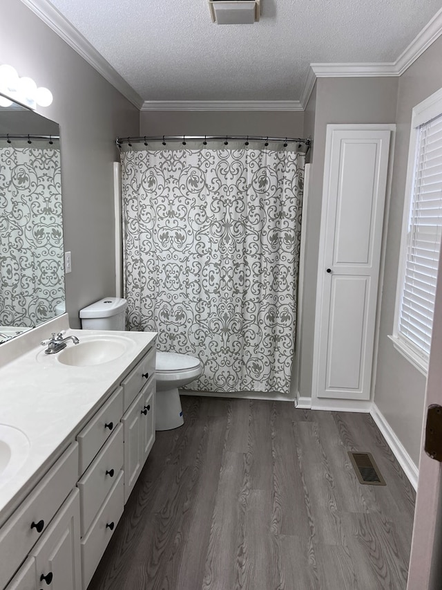 bathroom featuring crown molding, a textured ceiling, toilet, vanity, and hardwood / wood-style flooring