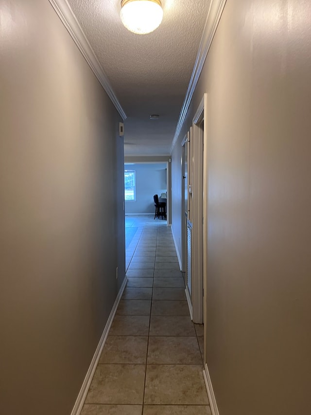 corridor with tile patterned floors, crown molding, and a textured ceiling