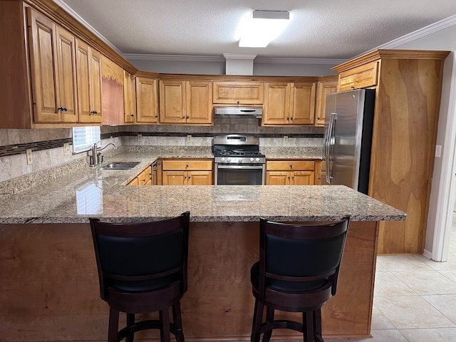 kitchen with a breakfast bar, sink, a textured ceiling, appliances with stainless steel finishes, and kitchen peninsula