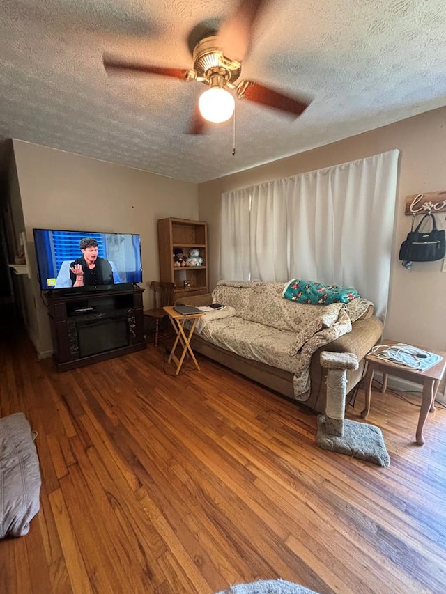 living room featuring ceiling fan, hardwood / wood-style floors, and a textured ceiling