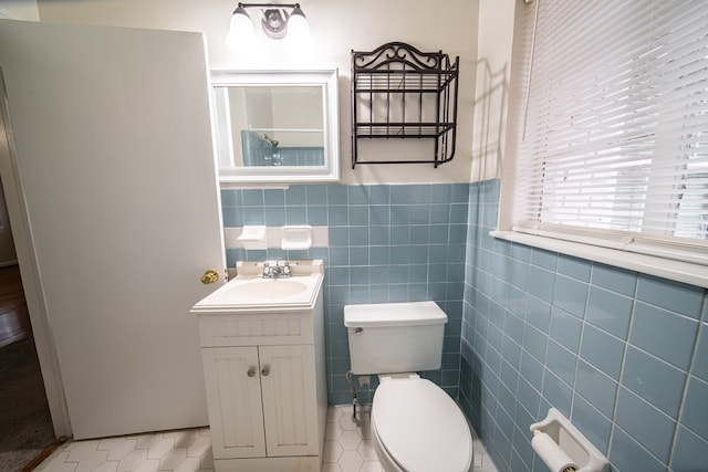 bathroom featuring tile patterned floors, vanity, tile walls, and toilet