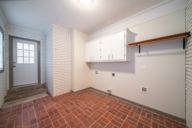 clothes washing area featuring cabinets, hookup for a washing machine, brick wall, crown molding, and electric dryer hookup