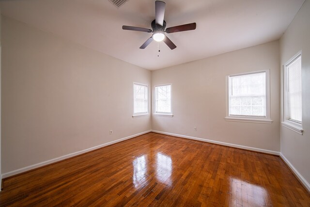 empty room with a healthy amount of sunlight, ceiling fan, and wood-type flooring