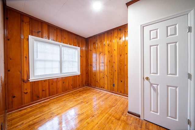 spare room with light hardwood / wood-style flooring and wood walls