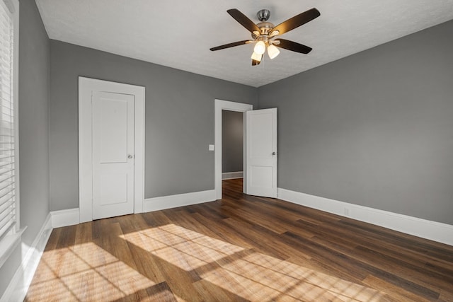 unfurnished bedroom featuring a ceiling fan, dark wood finished floors, a textured ceiling, and baseboards