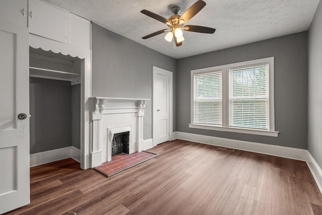 unfurnished living room featuring a textured ceiling, a fireplace, baseboards, and wood finished floors