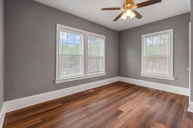 spare room featuring dark wood-type flooring, visible vents, and baseboards