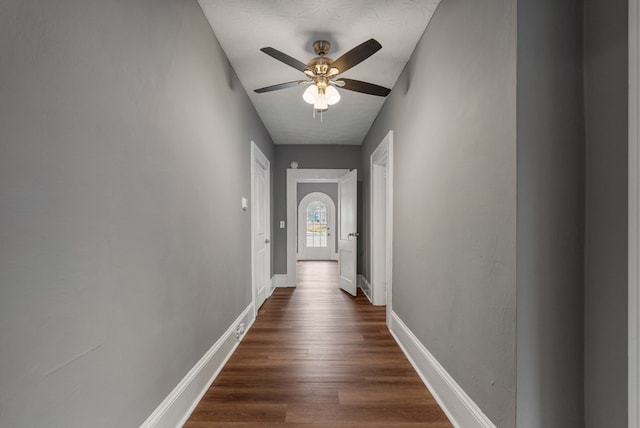 hall with dark wood-style flooring and baseboards