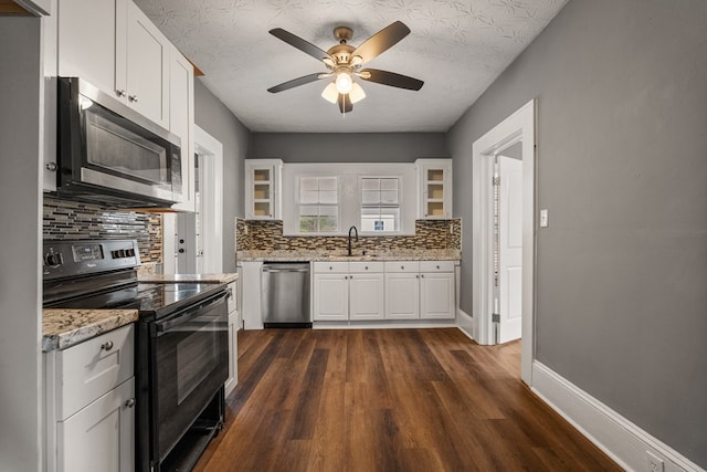 kitchen featuring stainless steel appliances, baseboards, white cabinets, dark wood finished floors, and glass insert cabinets