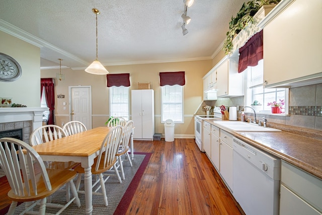 kitchen featuring plenty of natural light, dark wood-style flooring, a sink, ornamental molding, and white appliances