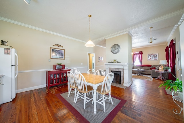 dining room featuring baseboards, a tile fireplace, ornamental molding, and hardwood / wood-style floors