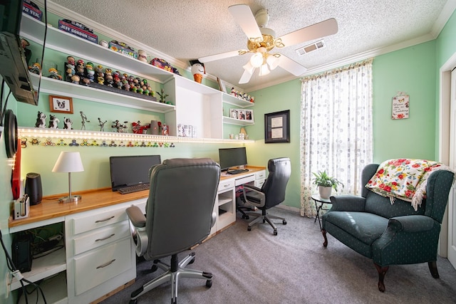 office space featuring ceiling fan, a textured ceiling, built in desk, ornamental molding, and carpet