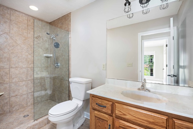 bathroom featuring a tile shower, vanity, a textured ceiling, and toilet