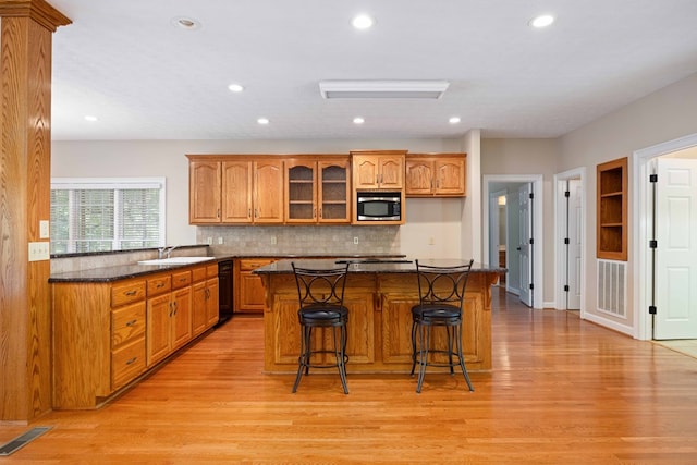 kitchen with a kitchen bar, light hardwood / wood-style flooring, stainless steel microwave, and sink