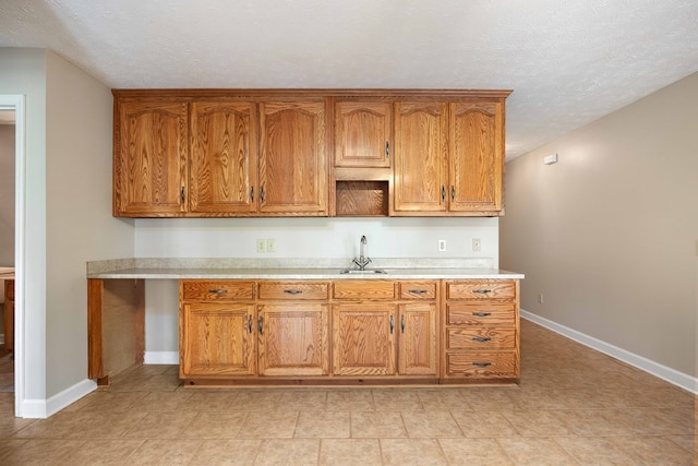 kitchen featuring sink, light tile patterned flooring, and a textured ceiling