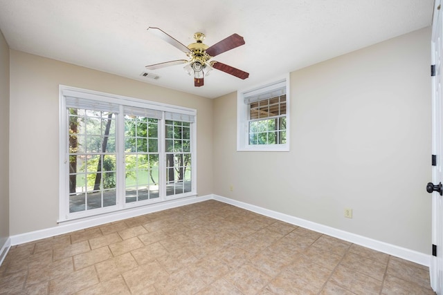 unfurnished room featuring a wealth of natural light, ceiling fan, and a textured ceiling