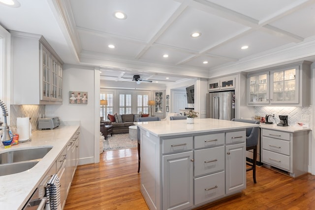 kitchen with a sink, a kitchen breakfast bar, high end fridge, and gray cabinetry