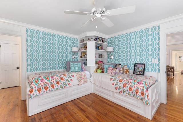 bedroom featuring wood finished floors, crown molding, and wallpapered walls