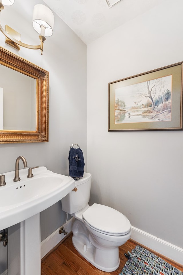 bathroom with toilet, a sink, baseboards, and wood finished floors