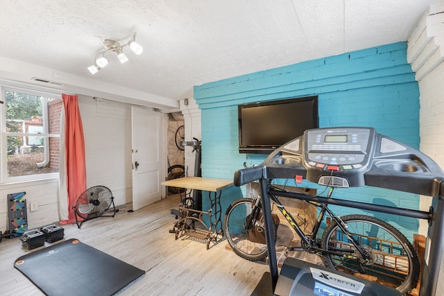 interior space featuring a textured ceiling, brick wall, and wood finished floors