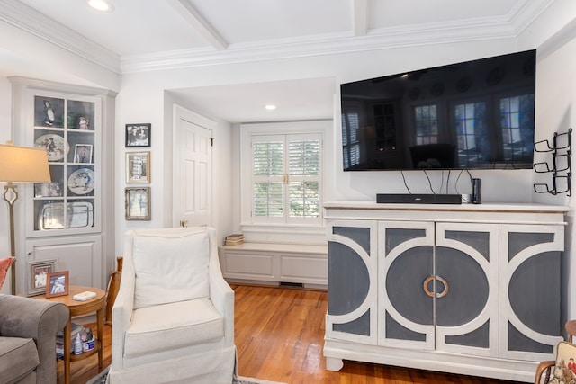 living area featuring ornamental molding, light wood-type flooring, and beam ceiling