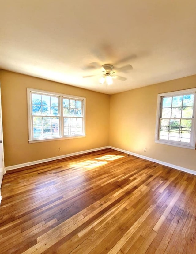 spare room with a ceiling fan, baseboards, and wood finished floors