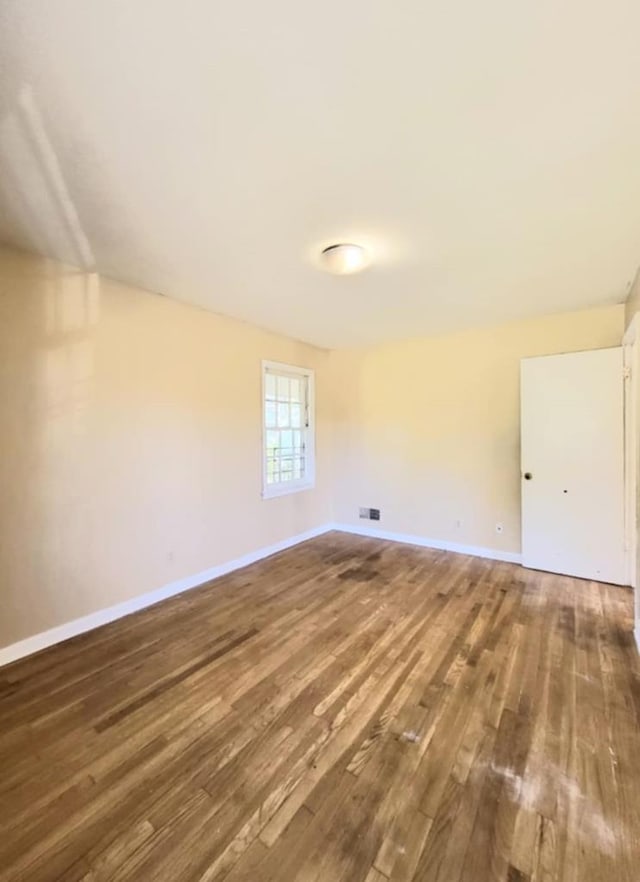 unfurnished room with baseboards and wood finished floors