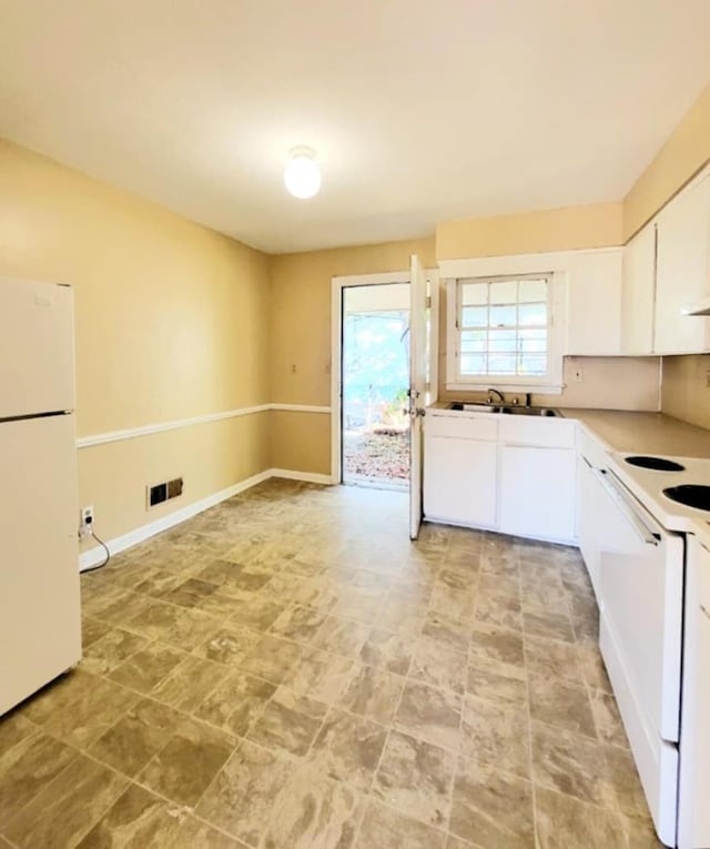 kitchen featuring baseboards, light countertops, white cabinets, and white appliances