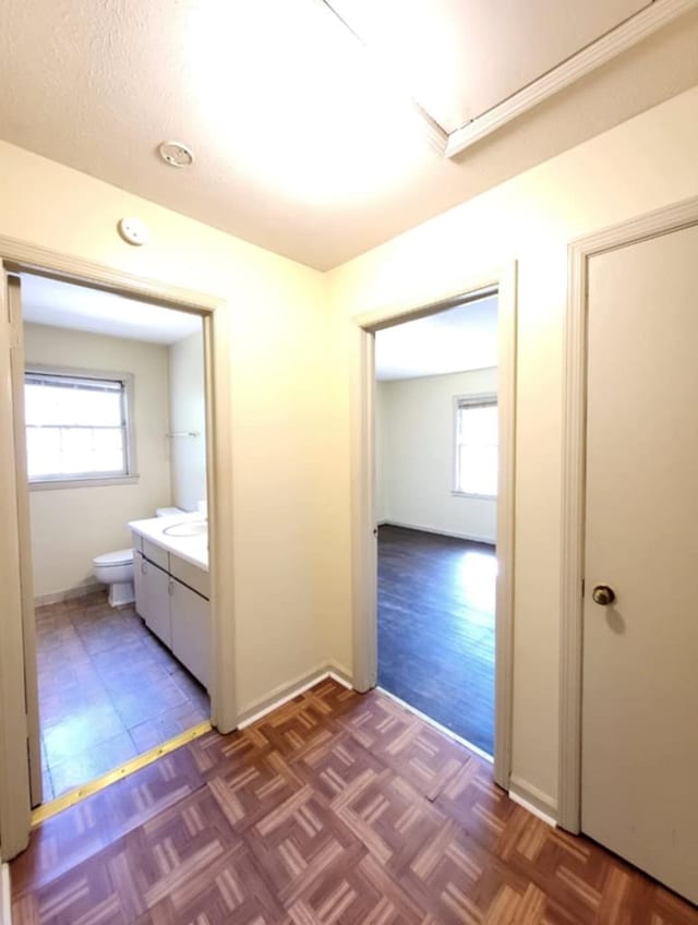 hall with baseboards and parquet floors