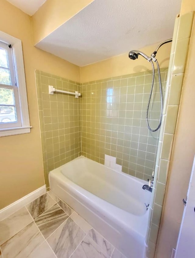 full bathroom with baseboards, bathtub / shower combination, a textured ceiling, and marble finish floor